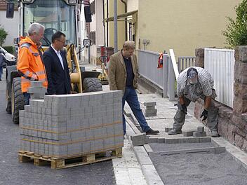 Der verbreiterte Gehweg kommt den Auraer Bürgern gelegen. Bauleiter Klaus-Peter Straub, Bürgermeister Thomas Hack und Baudirektor Jürgen Eisentraut betrachten die Arbeit des Pflasterers der Firma Hell.  Fotos: Winfried Ehling