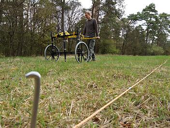 Nils Ostermeier schiebt den Handwagen mit den Magnetometer-Sonden über die abgesteckte Fläche. Foto: Arkadius Guzy