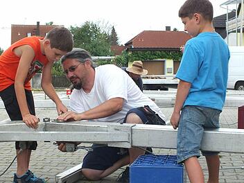Markus Ort hilft mit seinen Söhnen Sebastian und Tizian beim Zeltaufbau. Foto: Manfred Welker