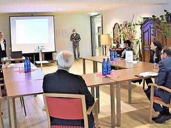 Kristin Steinlein (stehend neben der Leinwand) stellte dem bayerischen Gesundheits- und Pflegeminister Klaus Holetschek (1. v. r., sitzend) in kleiner Runde das „Inkludierte Springerprojekt" vor, das im Diakonie-Seniorenzentrum Martin Luther aktuell mit Unterstützung der Evangelischen Landeskirche Bayern umgesetzt wird.