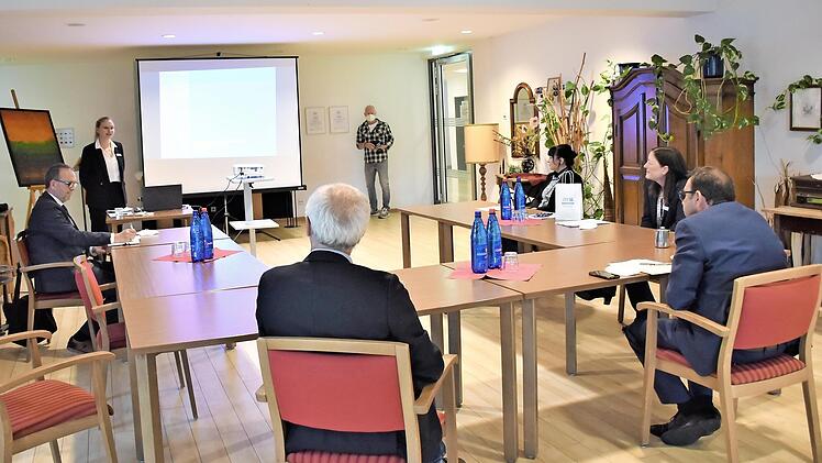 Kristin Steinlein (stehend neben der Leinwand) stellte dem bayerischen Gesundheits- und Pflegeminister Klaus Holetschek (1. v. r., sitzend) in kleiner Runde das „Inkludierte Springerprojekt" vor, das im Diakonie-Seniorenzentrum Martin Luther aktuell mit Unterstützung der Evangelischen Landeskirche Bayern umgesetzt wird.