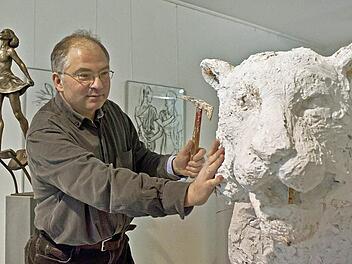 Der Bildhauer Andreas Krämmer bei der Arbeit an einem lebensgroßen Gipsmodell eines Tigers. Im Hintergrund die Bronzestatue einer Tänzerin, die von Krämmers Begeisterung für die Arbeit der Tanz-Compagnie von Pina Bausch kündet. Foto: Jochen Berger