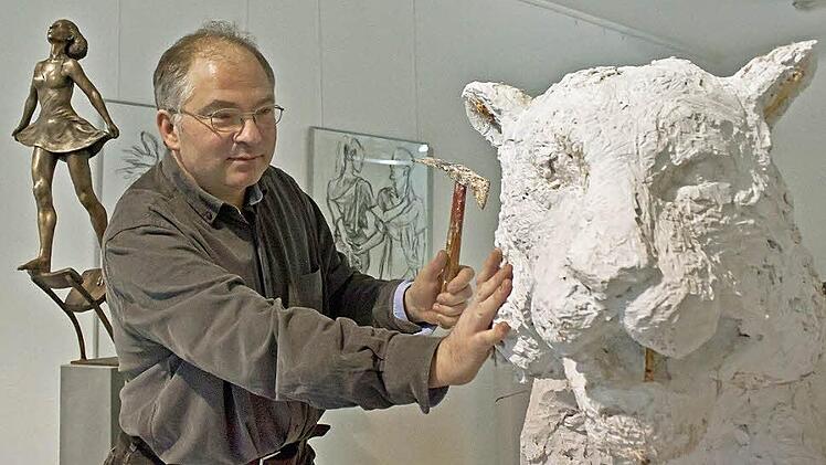 Der Bildhauer Andreas Krämmer bei der Arbeit an einem lebensgroßen Gipsmodell eines Tigers. Im Hintergrund die Bronzestatue einer Tänzerin, die von Krämmers Begeisterung für die Arbeit der Tanz-Compagnie von Pina Bausch kündet. Foto: Jochen Berger