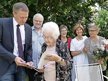Rödentals Bürgermeister Marco Steiner bringt Erika Sauer die Glückwünsche der Stadt und die Gratulation des bayerischen Ministerpräsidenten Markus Söder. Die Kinder Georg, Anne-Brigitte, Jutta und Heidi (von links) zeigen sich beeindruckt.  Foto: Manja von Nida
