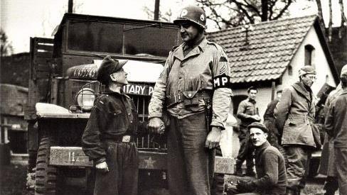 Links: Die Aufnahme vom April 1945 erinnert an die kurze Zeit der "Werwölfe" aus dem Landkreis Kronach und entstand nach der Gefangennahme der Nachwuchssoldaten. Ein amerikanischer Militärpolizist der 11. Armed Division hält dem damals 15-jährigen Philipp Reißenweber (Gemeinde Stockheim) die Hand. Der Schnappschuss. Rechts: Die Uniformverbrennung vor dem alten Kronacher Rathaus nutzten die Amerikaner zu Propagandazwecken in den USA. Repros: Gerd Fleischmann