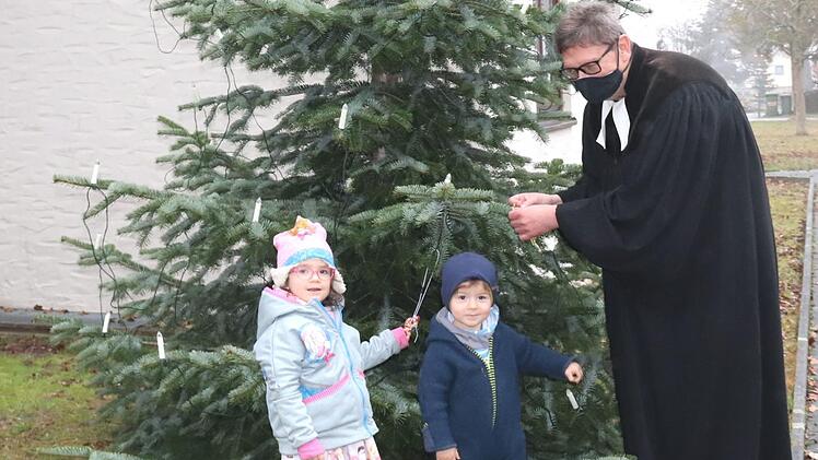Valerie und Willibald schmücken zusammen mit ihrem Opa, Pfarrer Fritz Schäfer, den "Mitmachbaum".       Foto: Johanna Blum