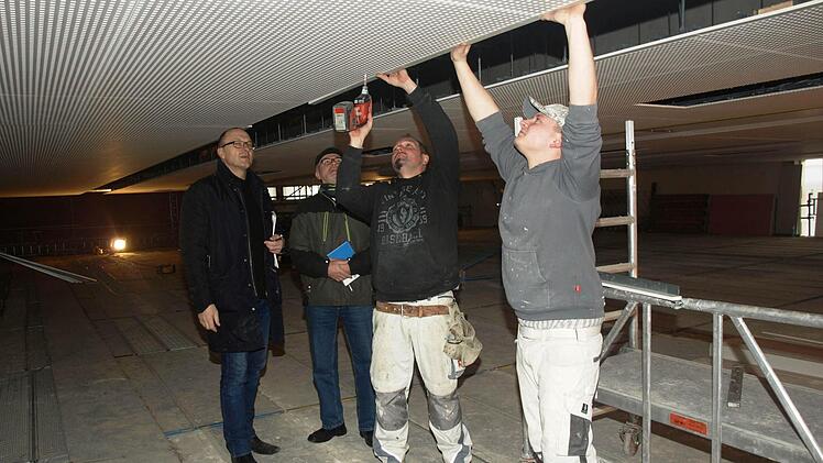 Viel Arbeit macht die neue Akustikdecke der Hegler-Halle. Sven Tischer und Sven Berninger (rechts) vom Farbenhaus Bruckmüller (Münnerstadt) montieren die Elemente. Architekt Johannes Messerschmitt (links) und 2. Bürgermeister Gerhard Fischer schauen zu.  Foto: Stefan Geiger