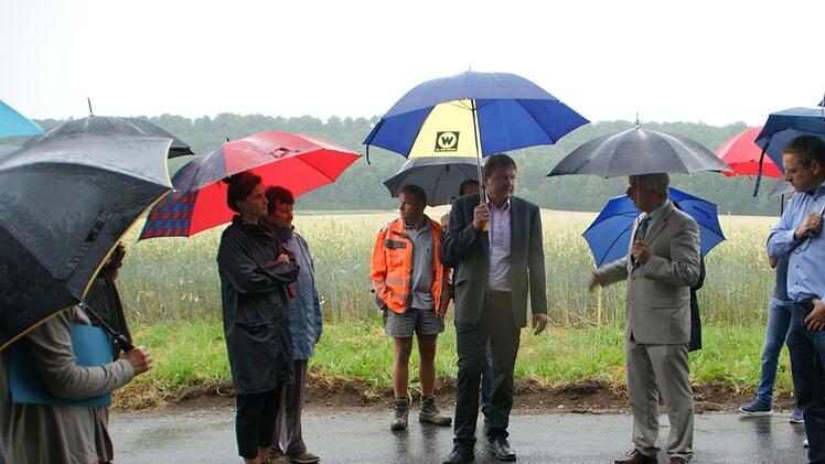 Im Regen erörterten stellvertretender Landrat Michael Ziegler, Bürgermeister Matthias Bäuerlein, Manfred Rott vom Staatlichen Bauamt und Alfons Schanz vom Kreis-Tiefbau (von rechts) mit den Fabrikschleichachern die Möglichkeiten, den Verkehr zu bremsen.  Fotos: Sabine Weinbeer