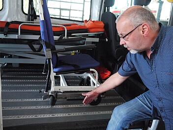 Die Fahrzeuge des Patienten-Fahrdiensts sind speziell ausgestattet. Zum Beispiel sind am Boden Schienen angebracht, um Rollstühle fest verankern zu können, wie Ingo Holzmann, stellvertretender Geschäftsführer des ASB im Kreis Kronach, zeigt. Foto: Rebecca Vogt