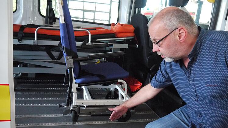 Die Fahrzeuge des Patienten-Fahrdiensts sind speziell ausgestattet. Zum Beispiel sind am Boden Schienen angebracht, um Rollstühle fest verankern zu können, wie Ingo Holzmann, stellvertretender Geschäftsführer des ASB im Kreis Kronach, zeigt. Foto: Rebecca Vogt