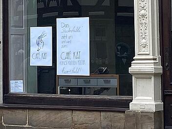Ein Schaufenster mit zwei Plakaten informiert &uuml;ber den Umzug des Kunst-Caf&eacute;s "Caf&eacute; K&auml;t". Kunst, K&uuml;che und Kultur werden an einem neuen Ort bald fortgef&uuml;hrt.