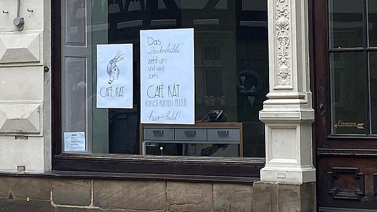 Ein Schaufenster mit zwei Plakaten informiert &uuml;ber den Umzug des Kunst-Caf&eacute;s "Caf&eacute; K&auml;t". Kunst, K&uuml;che und Kultur werden an einem neuen Ort bald fortgef&uuml;hrt.