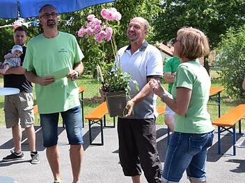 Jeder Gastgeber erhielt als kleines Dankeschön einen Blumenstock. Im Bild überreicht der Vorsitzende Armin Hahn (links) zusammen mit seiner Frau Sabina einen Blumenstock an Gastgeber Hubert Schneider (Mitte), der seinen Garten unter dem Motto "Wein und Meer" präsentierte.  Foto: Horst Conze