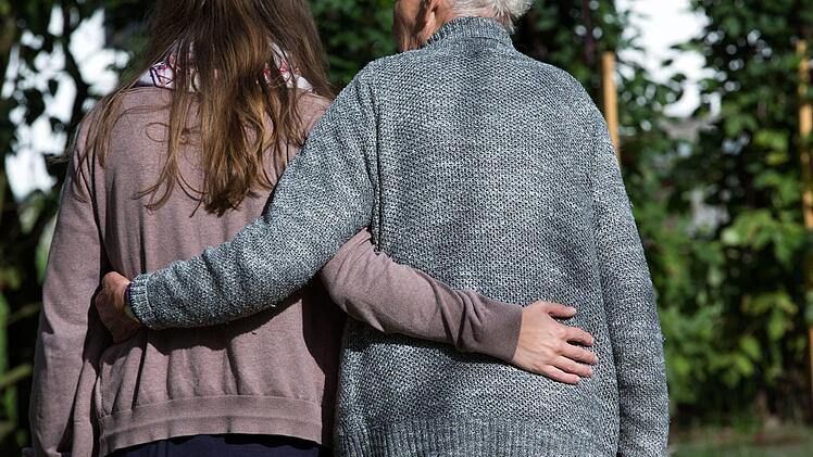 Eine Frau und ein &auml;lterer Mann gehen durch einen Garten. Symbolbild, Foto: Jens B&uuml;ttner/dpa