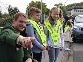 Verkehrserzieher Stefan Löhser zeigt den Abc-Schützen Hannes und Lavinia das richtige Verhalten beim Überqueren der Straße.  Foto: Ralf Ruppert