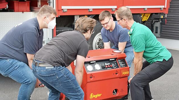 Frank Schnabel (rechts) zeigt den Lehrgangsteilnehmern die richtige Standposition beim Heben einer Feuerwehrpumpe von annähernd 150 Kilogramm Gewicht.