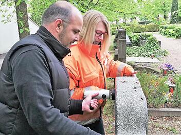 Friedhofsverwalter Stefan Krieg und Mitarbeiterin Carmen Goll pressen den Kipp-Tester an die Oberkante eines Grabsteins.