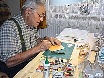 Klebstoffe, Scheren, Schreibstifte, Cuter-Messer, Lupen und Licht, sind für die Arbeit von Manfred Beilner, hier an seinem Arbeitstisch, für sein Bastelhobby unentbehrlich. Vor ihm entsteht das Schlachtschiff "S.M.S. Victoria Louise".  Foto: Helmut Will