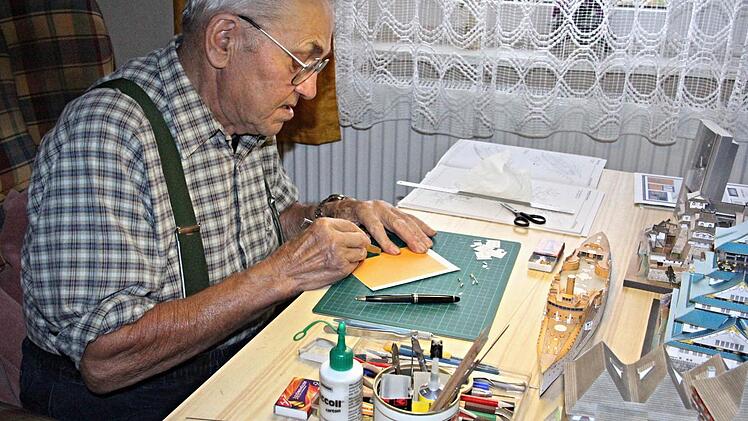 Klebstoffe, Scheren, Schreibstifte, Cuter-Messer, Lupen und Licht, sind für die Arbeit von Manfred Beilner, hier an seinem Arbeitstisch, für sein Bastelhobby unentbehrlich. Vor ihm entsteht das Schlachtschiff "S.M.S. Victoria Louise".  Foto: Helmut Will