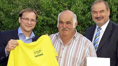 40 Jahre in der FDP: dafür gab es für Manfred Dittmar ((mitte) vom FDP-Bezirksvorsitzenden MdL Karsten Klein (links) das obligatorische gelbe T-Shirt, Bad Kissingens Kreisverbandsvorsitzender Hans-Joachim Hofstetter überreichte Urkunde und Medaille.  Foto: Peter Rauch