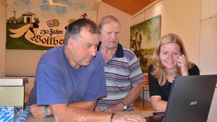 Drei Generationen organisieren mittlerweile die Kirmes in Wollbach. Hier zeigen Erwin und Natascha Below Wolfgang Rottenberger (Mitte) Fotos von dem vergangenen Fest. Foto: Kathrin Kupka-Hahn