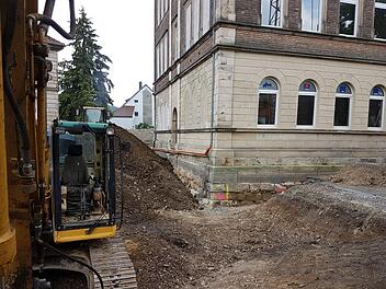 Die Bagger graben um das VHS-Gebäude den Boden auf, unter anderem um den Anbau vorzubereiten und das Fundament zu verstärken. An der Gebäudeseite sind zugemauerte Fenster zu sehen, hinter denen eine Überraschung schlummerte. Foto: Marco Meißner
