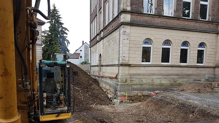 Die Bagger graben um das VHS-Gebäude den Boden auf, unter anderem um den Anbau vorzubereiten und das Fundament zu verstärken. An der Gebäudeseite sind zugemauerte Fenster zu sehen, hinter denen eine Überraschung schlummerte. Foto: Marco Meißner