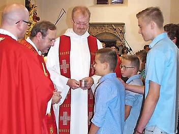 Christian empfängt durch Domkapitular Norbert Jung das Heilige Sakrament der Firmung. Mit auf dem Bild sind Kaplan Sven Raube (links) und Regionaldekan Thomas Teuchgräber (Mitte).  Foto: Heike Schülein