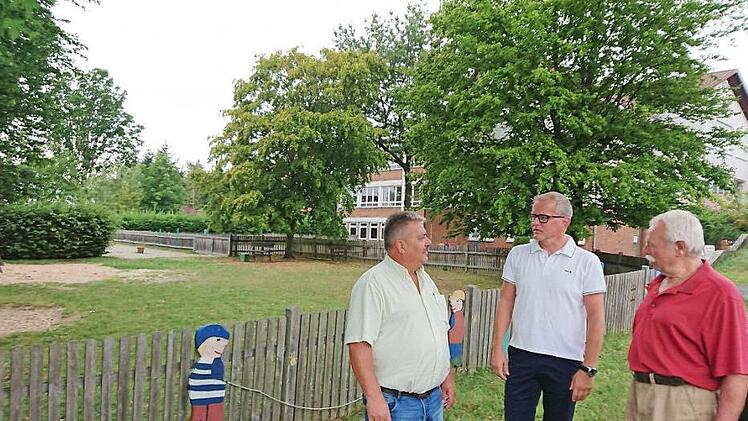 Georg Habermann, Ralf Olmesdahl und Josef Staudigel (von links) wollen sich nicht so schnell damit abfinden, dass das alte Aischer Schulhaus (im Hintergrund) abgerissen und auf dem Spielplatz (links) ein neuer Kindergarten gebaut werden soll.  Fotos: Andreas Dorsch
