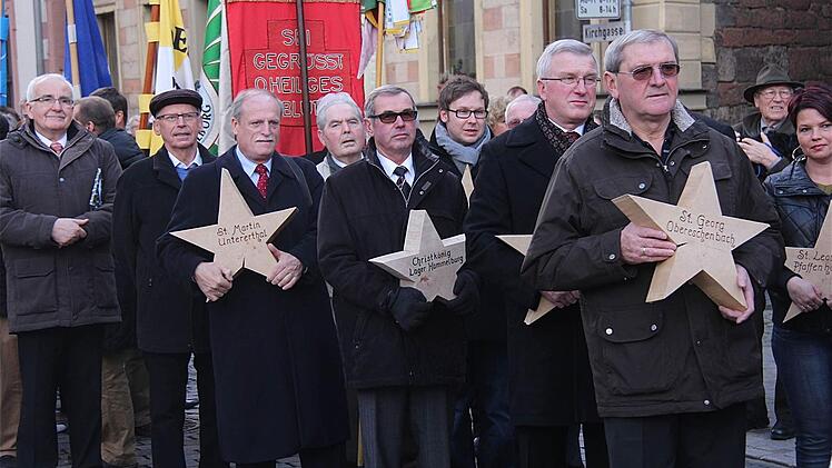 Abordnungen der zur Pfarreiengemeinschaft gehörenden Ortsteile geleiten den neuen Pfarrer vom Marktplatz zur Kirche.