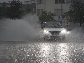 Ein Auto fährt bei starkem Regen auf einer überfluteten Straße. Foto: Andreas Rosar/dpa