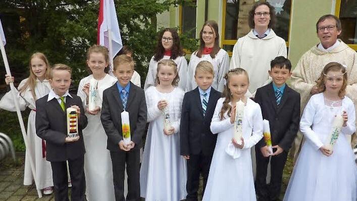 Annika Büsch, Lina Detsch, Jamie Martin, Emily Pötzinger, Elias Renk, Marie Schubert, Anton Schülner und Jakob Wachter feierten ihre Erstkommunion. Mit im Bild sind Gemeindereferent Matthias Beck, Pfarrer Hans-Michael Dinkel (rechts) sowie einige Ministranten. Foto: Gerd Fleischmann