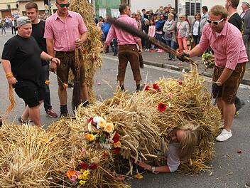 Mit dem Besen wird der Strohbär hier zum Ablassen von dem Mädchen gepeitscht. Foto: Günther Geiling
