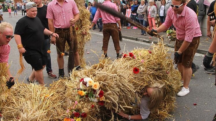 Mit dem Besen wird der Strohbär hier zum Ablassen von dem Mädchen gepeitscht. Foto: Günther Geiling