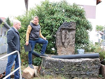 Bürgermeister Michael Kastl (links) und Ortsreferent Fabian Nöth im Gespräch am Reichenbacher Dorfbrunnen. Der erhält eine Wasserspielfläche. Versetzt werden muss er ohnehin. Foto: Thomas Malz.