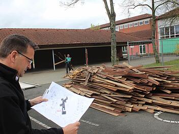 Bürgermeister Karsten Fischkal inspiziert den Lageplan für die neue Kinderkrippe, die an dieser Stelle auf dem Schulgelände entstehen soll. Um Platz für den Neubau zu schaffen, wurde mit dem Abriss der ehemaligen Fahrradhalle (im Hintergrund) begonnen. Foto: Andreas Dorsch
