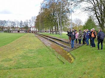 Der Bausenat besichtigt die Freisportanlage. Wo früher die Laufbahn war, ist gerade noch so zu erkennen. Sie soll normgerecht neu erstellt werden, der Fußballplatz soll einen Kunstrasen bekommen. Foto: Rainer Lutz