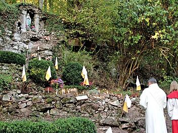 In einer Steilwand wurde von den Bürgern in der Kriegszeit diese Mariengrotte errichtet. An dem kerzengeschmückten Ort versammelten sich Diakon Joachim Stapf und die Gläubigen im Gebet. Foto: Günther Geiling