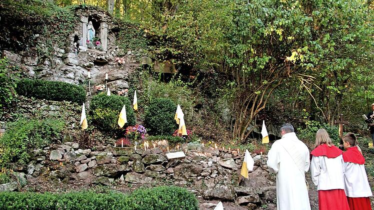 In einer Steilwand wurde von den Bürgern in der Kriegszeit diese Mariengrotte errichtet. An dem kerzengeschmückten Ort versammelten sich Diakon Joachim Stapf und die Gläubigen im Gebet. Foto: Günther Geiling