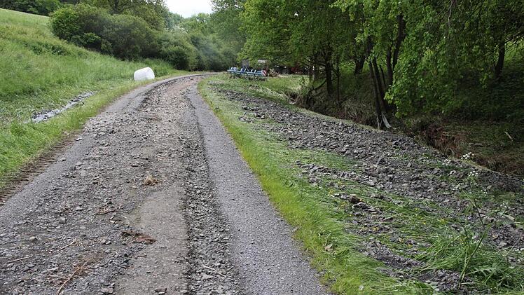 Der Flurbereinigungsweg wurde ausgeschwemmt. Geröll und Split liegt daneben im grünen Seitenstreifen.