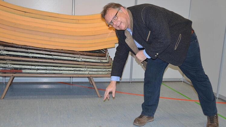 Martin Stingl zeigt einen Rostfleck vom Fuß eines Feldbetts. Mehr Schaden hat der Hallenboden nicht genommen.