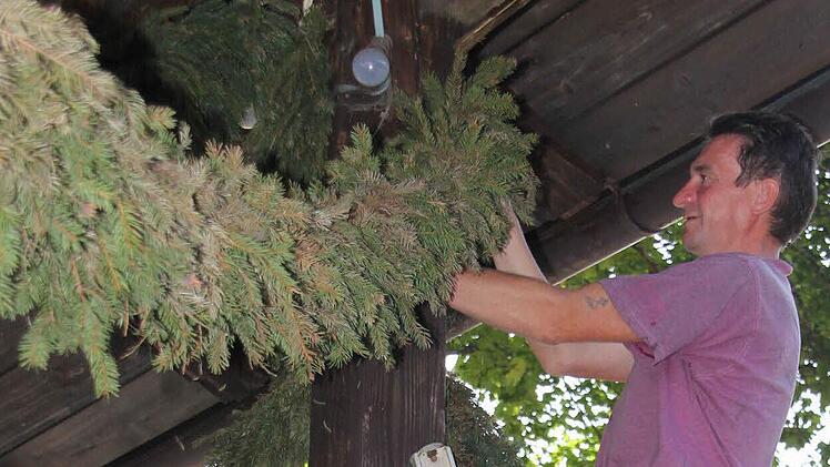 Andreas M&uuml;nzel nimmt den Gr&uuml;nschmuck am Pavillon ab. Fotos: Corinna Igler