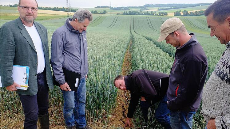 Die Trockenheit hinterlässt deutliche Spuren: Manche Risse in der Erde sind bereits richtig tief, wie Erzeugerring-Fachberater Stefan Karch (Mitte) demonstriert. Ihm zur Seite stehen (von links) Naturland-Berater Werner Vogt-Kaute, Rainer Schubert (Wasserforum), Erzeugerring-Fachberater Sebastian Ries und der Ramsthaler Landwirt Leo Warmuth. Foto: Gerd Schaar