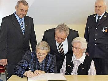 Theresia Regenfus (links) und Rita Schütz tragen sich ins Goldene Buch ein. Mit im Bild Georg Regenfus, Bürgermeister Franz Schmidtlein und Erwin Wagner. Foto: fra-press