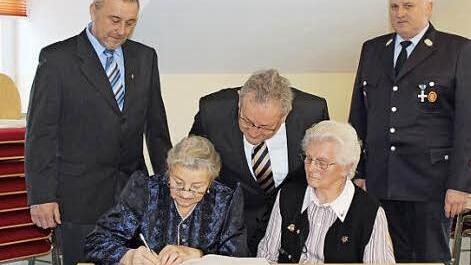 Theresia Regenfus (links) und Rita Schütz tragen sich ins Goldene Buch ein. Mit im Bild Georg Regenfus, Bürgermeister Franz Schmidtlein und Erwin Wagner. Foto: fra-press