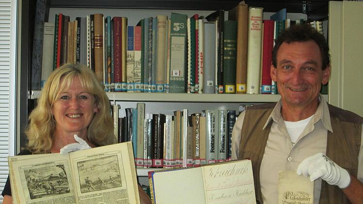 Die Archivare der Stadt Hammelburg, Elfriede Böck und Thomas Mendel, mit der "Hausvater"-Literatur, der Schulkladde von 1865 und der Jahresrechnung des Orts Pfaffenhausen aus 1781.Winfried Ehling
