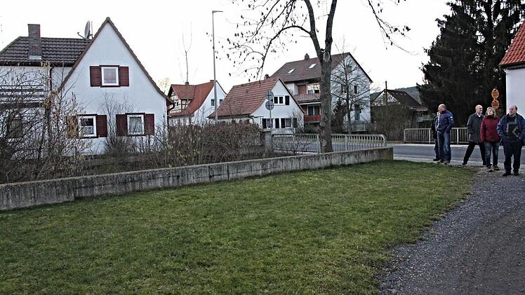 Sträucher und Bäume entlang des Baches (links) sollten die Sichtverhältnisse an der Ausfahrt, wo Mitglieder des Bauausschusses stehen, verbessern. Gefällt werden aber nur ein oder zwei Bäume die in das Grundstück (links) hinein ragen. Foto: Helmut Will