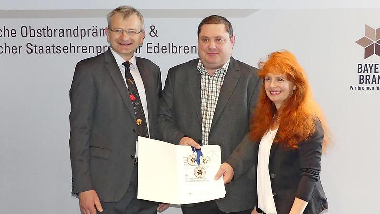 Der Vorsitzende des fränkischen Kleinbrennerverbandes Hubert Fröhlich (von links) überreicht Holger Schulz von der Edelobstbrennerei in Neuses die Urkunde - mit auf dem Bild die Geschäftsführerin des fränkischen Kleinbrennerverbandes, Andrea Baetz. Foto: privat