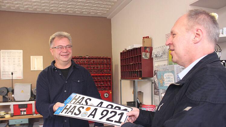 Thomas Hümmer (rechts) nimmt seine frisch gedruckten Autoschilder für sein wasserstoffbetriebenes Auto in Haßfurt entgegen. Jutta Rudel