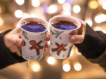 Zwei Frauen stoßen mit Glühwein gefüllten Bechern an. Statt auf dem Weihnachtmarkt trinkt man jetzt den Glühwein Zuhause. Dazu bestellt man Lebkuchen und Weihnachtsdeko im Internet. Foto: Christoph Schmidt, dpa